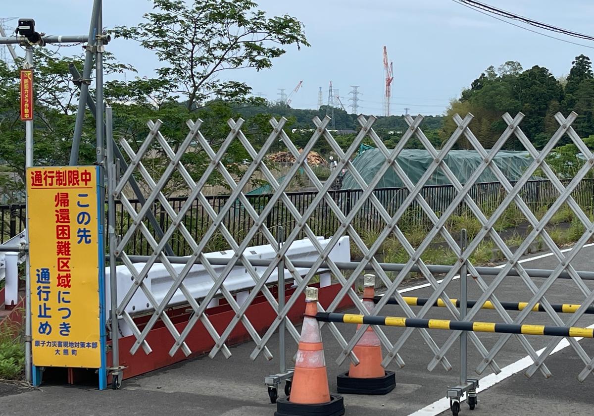 Debido a la alta radiación en el suelo, una valla corta la carretera a la central nuclear de Fukushima 1, cuyas grúas se ven al fondo y donde el tsunami de 2011 fundió tres de sus reactores