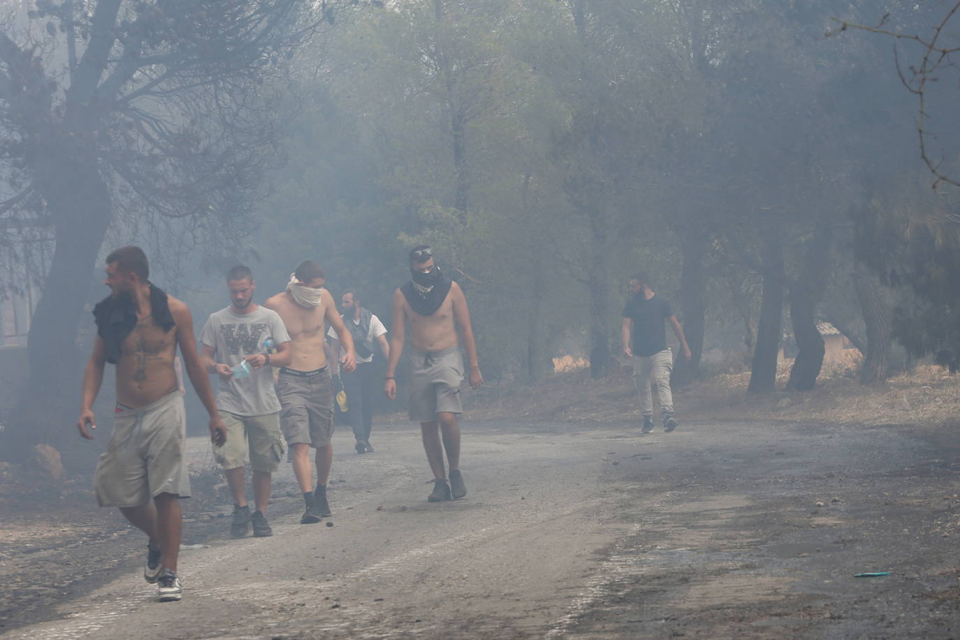 Los residentes caminan entre el humo en la aldea de Agia Paraskevi (Grecia)