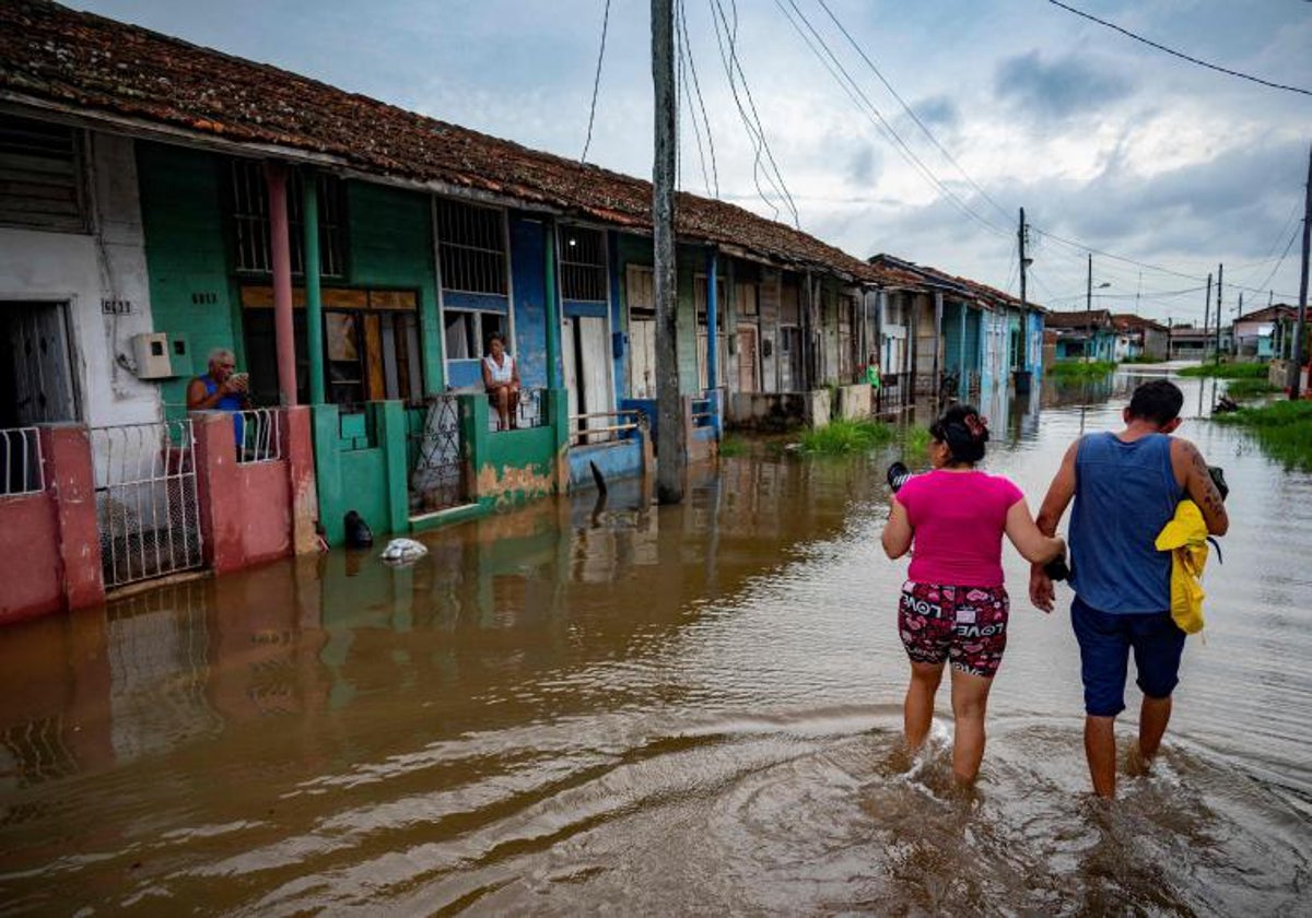 Personas caminan en una zona inundada de la provincia de Mayabeque (Cuba) tras el paso del huracán Idalia