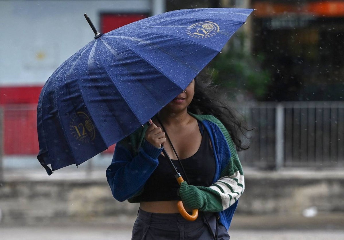 Una mujer se protege de la lluvia y los fuertes vientos provocados por el supertifón Saola en la isla de Lantau, en Hong Kong