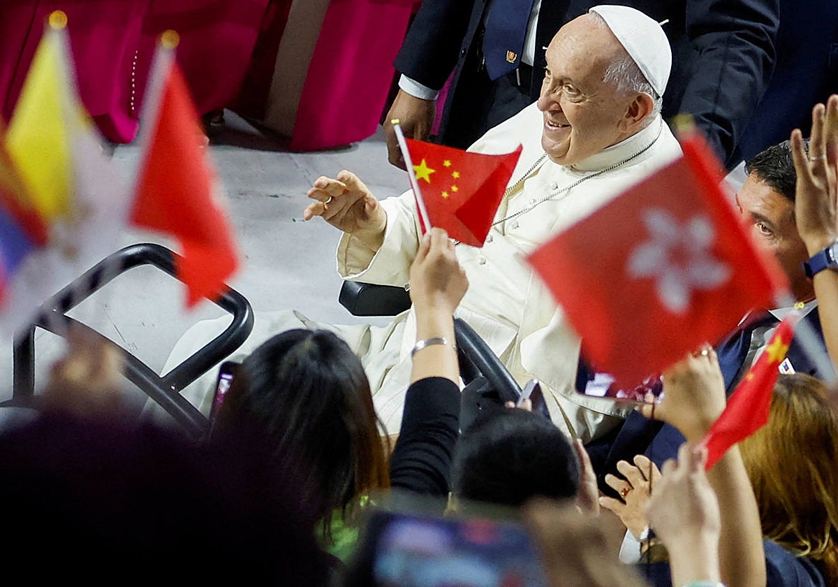La gente ondea banderas chinas y de Hong Kong, mientras el Papa Francisco llega para asistir a la Santa Misa en el Steppe Arena