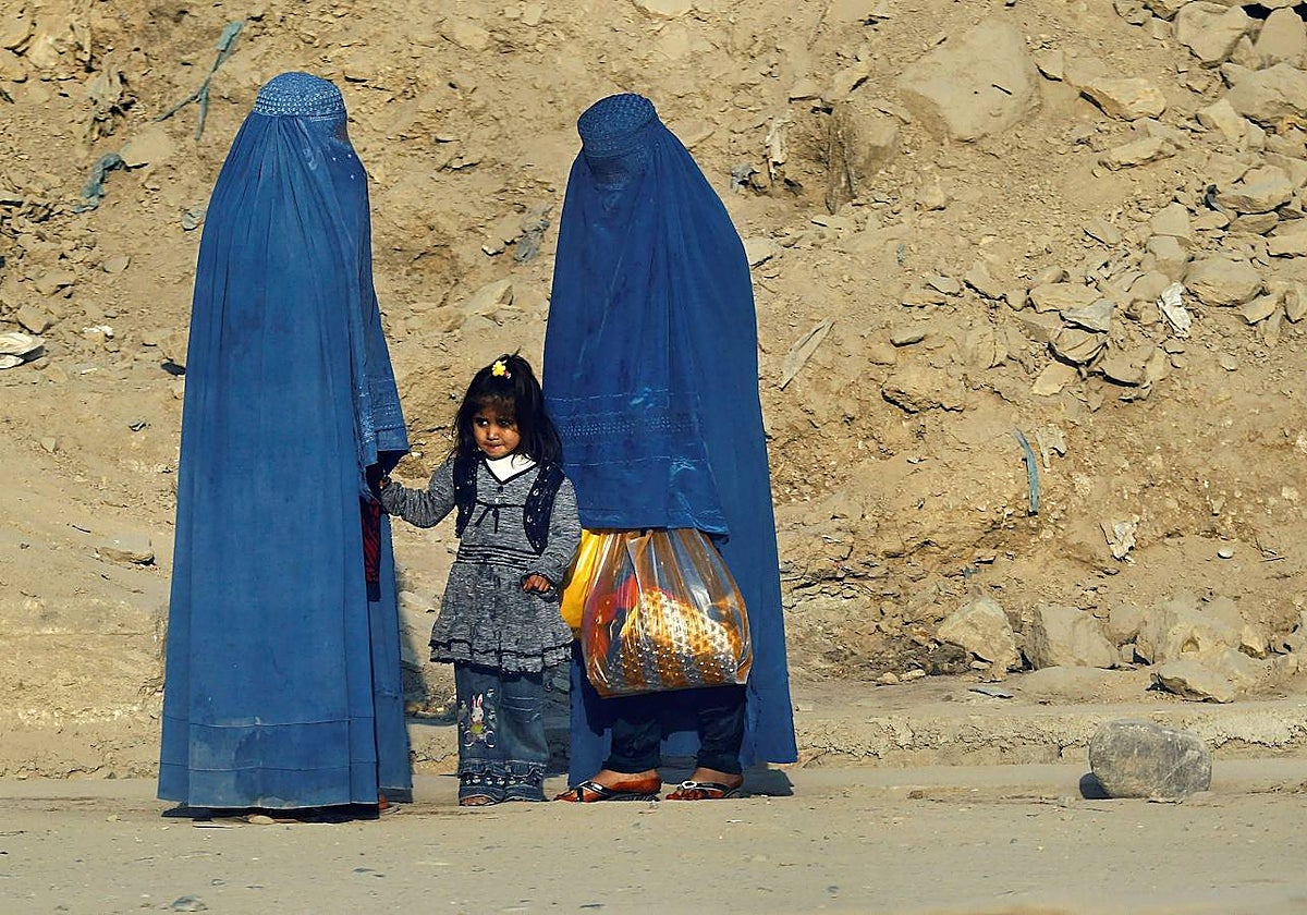 Mujeres afganas vestidas con burka esperan el transporte en una carretera de Kabul