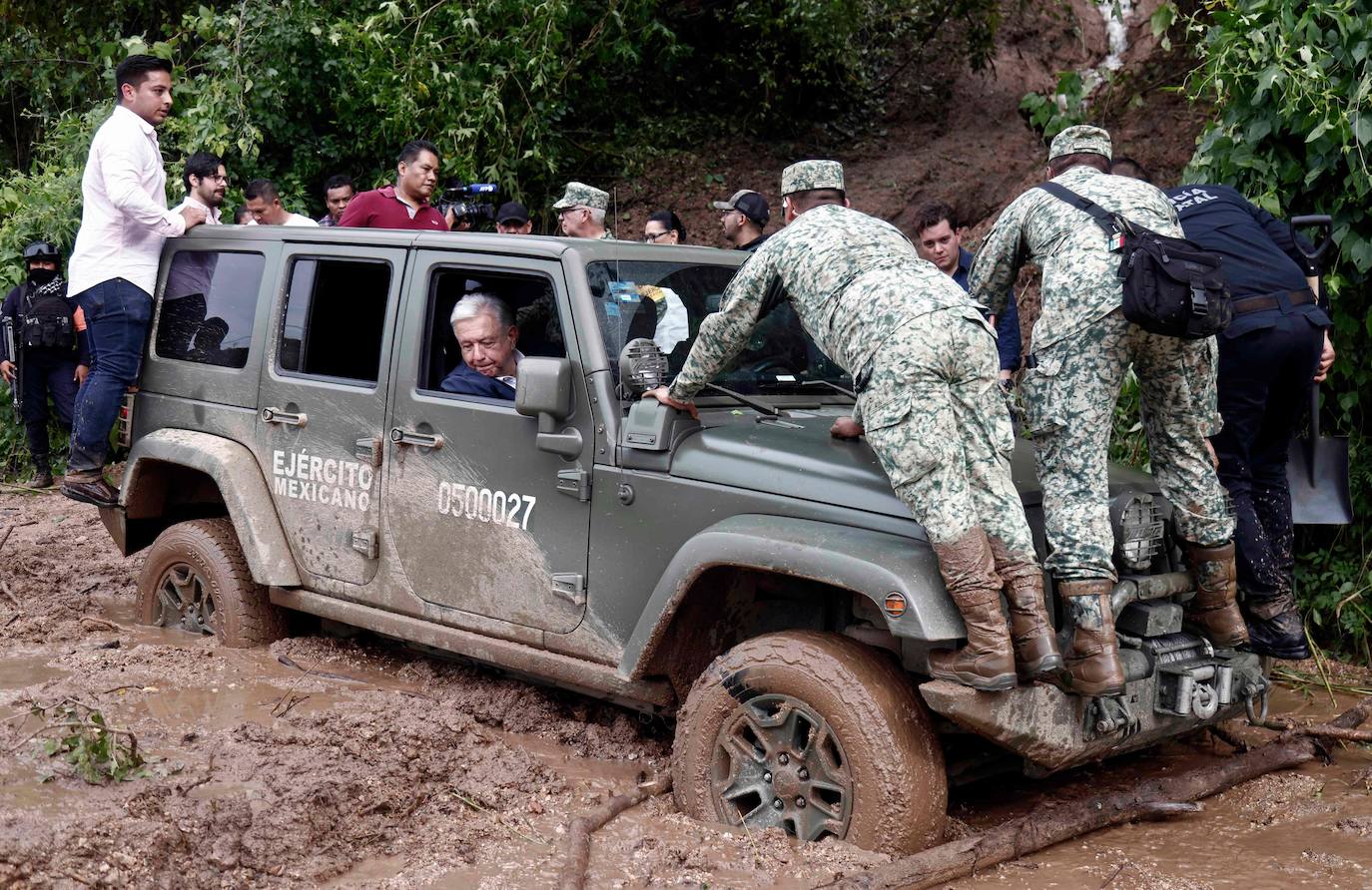 El presidente de México, Andrés Manuel López Obrador, mira por la ventanilla mientras el vehículo que le transporta se queda atascado en el barro durante una visita al Kilómetro 42