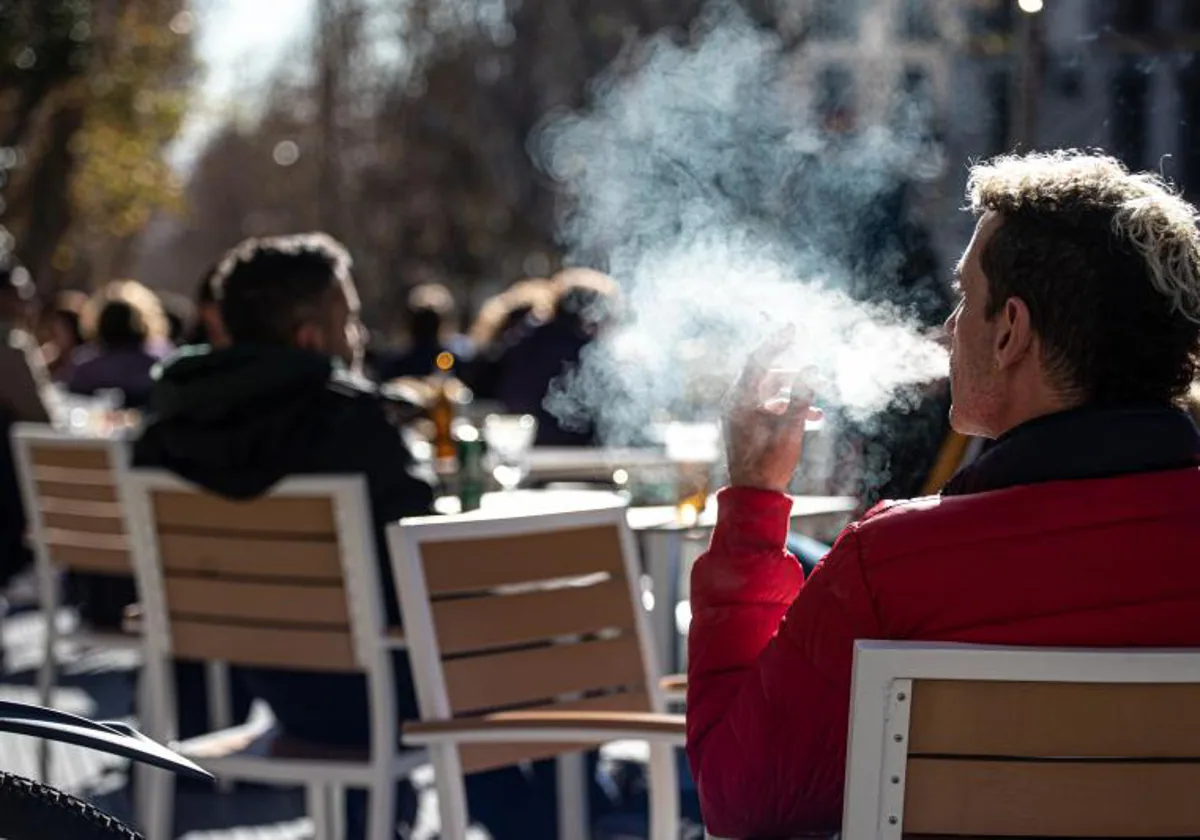 Un hombre fuma en una terraza de un bar