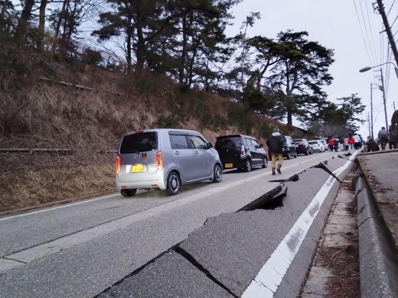 La gente camina por una carretera dañada por un terremoto, en Wajima
