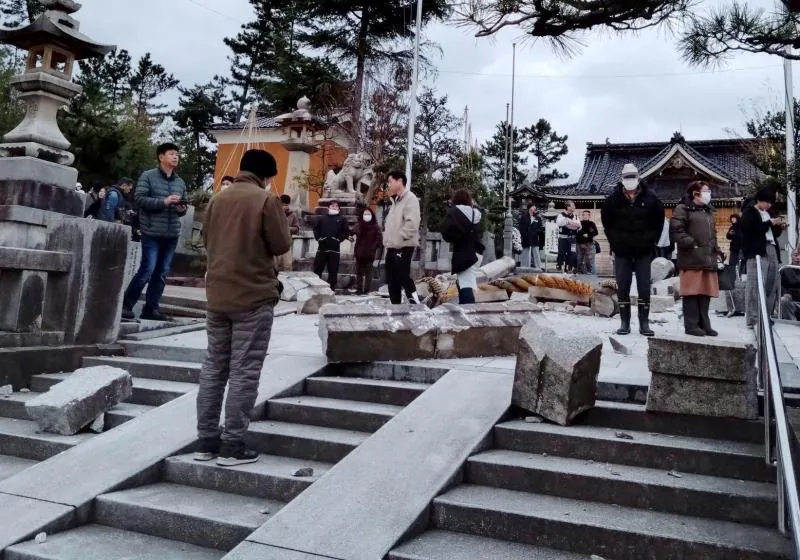 Personas cerca de una puerta torii derrumbada causada por un terremoto en el Santuario Onohiyoshi en Kanazawa