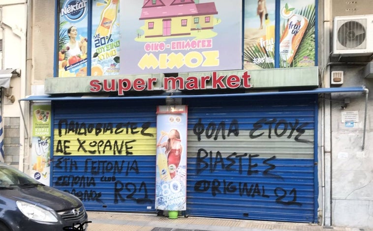 Imagen principal - Las puertas del supermercado de Illías Mijos con varias pintadas alusivas a los motivos por lo que había sido detenido, en la parte superior. Por debajo, las armas que le fueron incautadas en el momento de su detención y un combo con imágenes de Mijos con políticos y personalidades griegas que el mismo había subido a sus redes sociales.