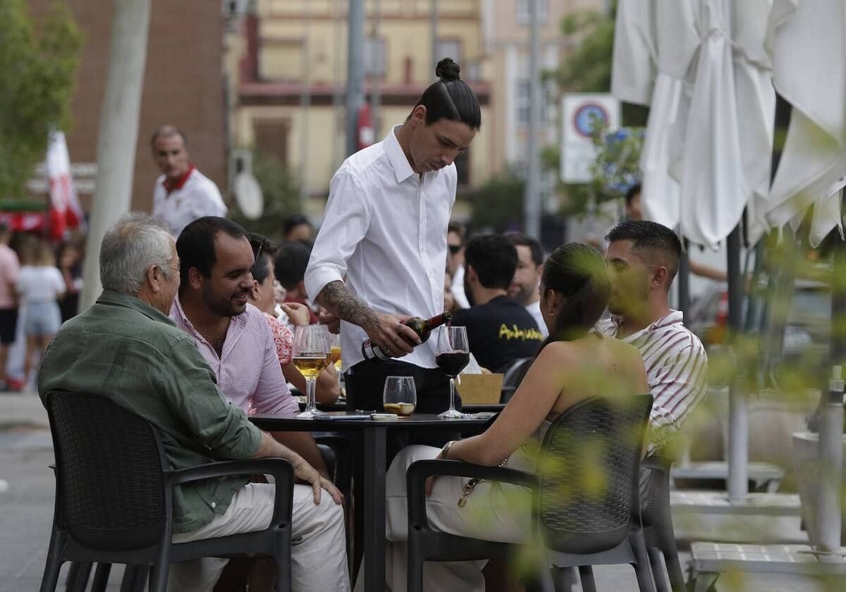 Un camarero joven sirve a unos clientes en Sevilla