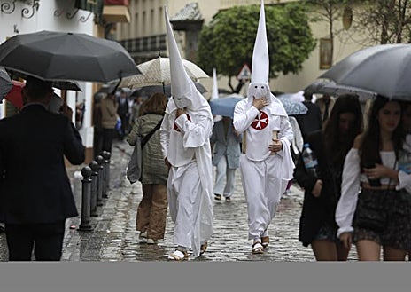 Imagen secundaria 1 - En la parte superior, los miembros de la cofradía Lágrimas y Favores de Málaga, con el actor Antonio Banderas en el centro, esperan la decisión de los hermanos mayores, que finalmente han optado por la suspensión. Debajo, a la izquierda, unos nazarenos de La Amargura de Sevilla, se recogen después del anuncio de la suspensión de la procesión por la lluvia. A la derecha, un costalero de la procesión de Nuestro Padre Jesús del Amor de Madrid, conocida como La Borriquita