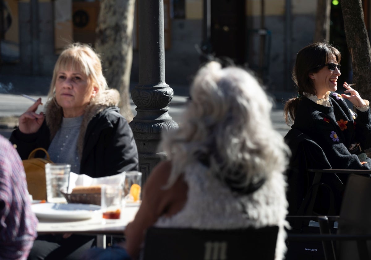 Varios clientes fuman en la terraza de un bar