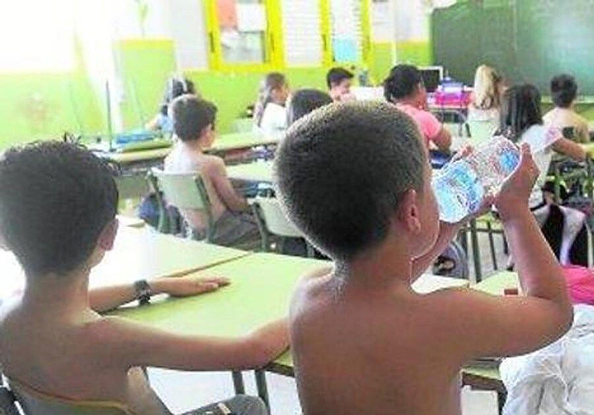 Un niño sin camiseta bebe agua para soportar las altas temperaturas en el aula, en una imagen de archivo