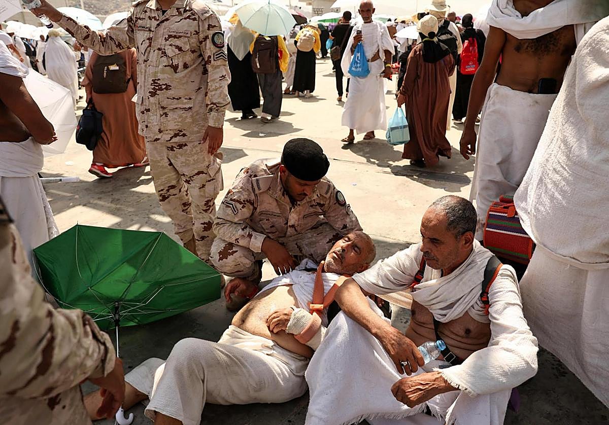 Un miembro de las fuerzas de seguridad saudíes ayuda a un hombre afectado por el calor abrasador en La Meca