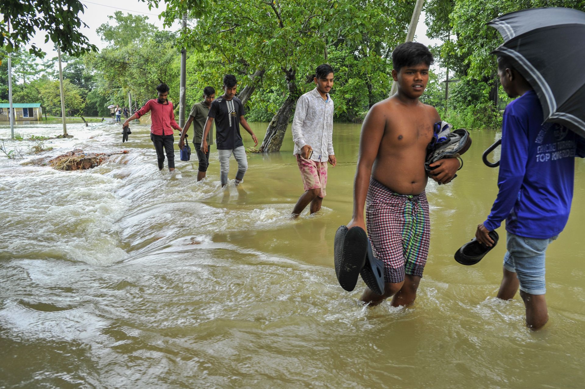 La gente camina por una carretera arrasada por las aguas de la inundación en la zona de Bangladesh