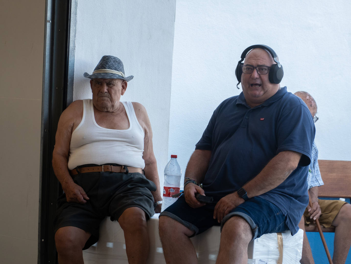 Dos personas siguen atentos la puja de los lotes de pescado y marisco en la lonja.