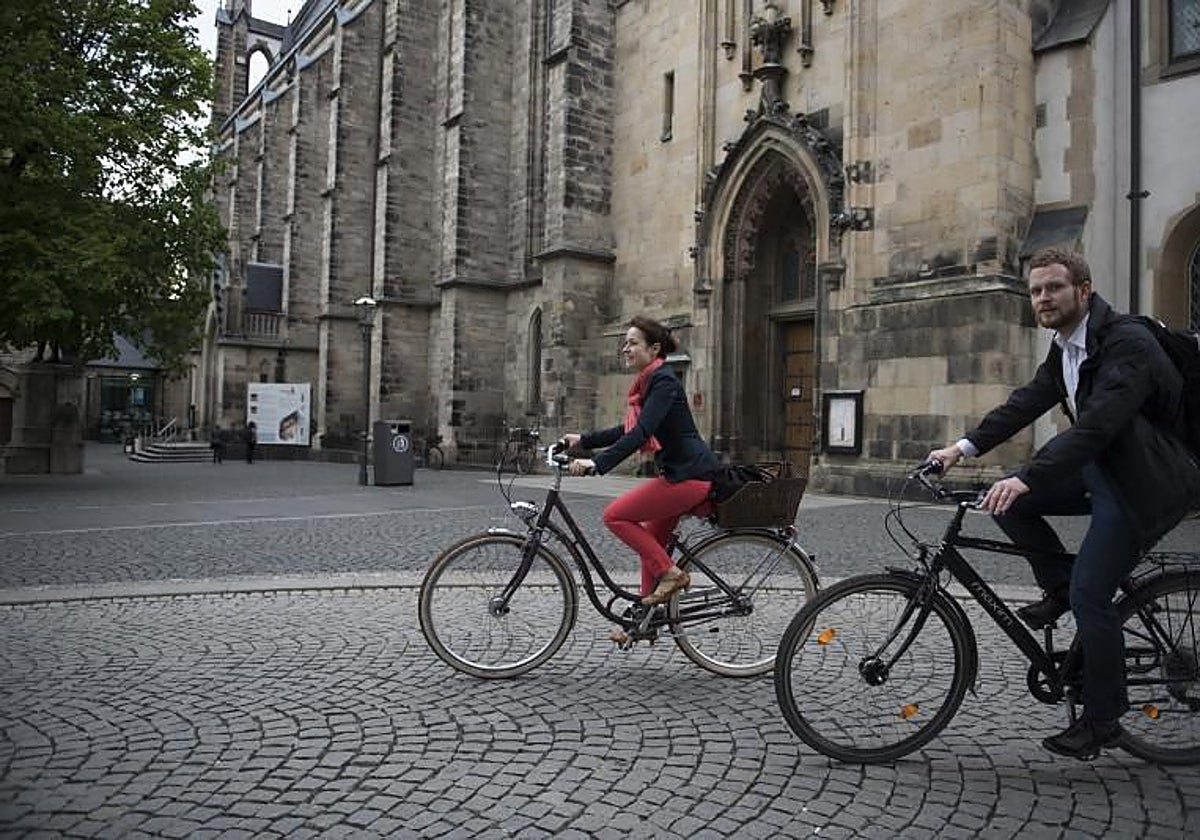 Unos jóvenes pasean en bici por delante de la iglesia de Santo Tomás de Leipzig (Alemania)