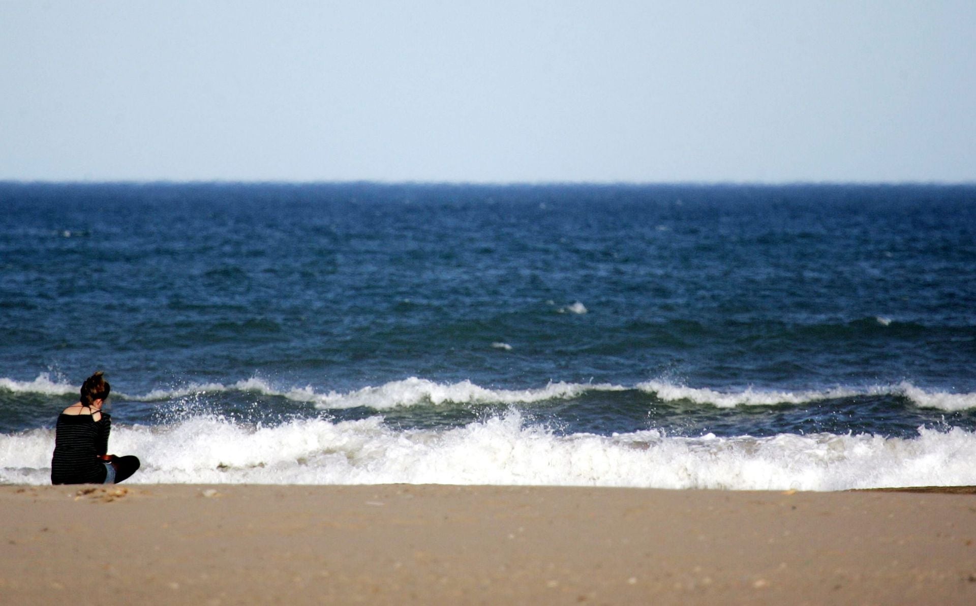 Una persona solitaria mira al mar, imagen archivo