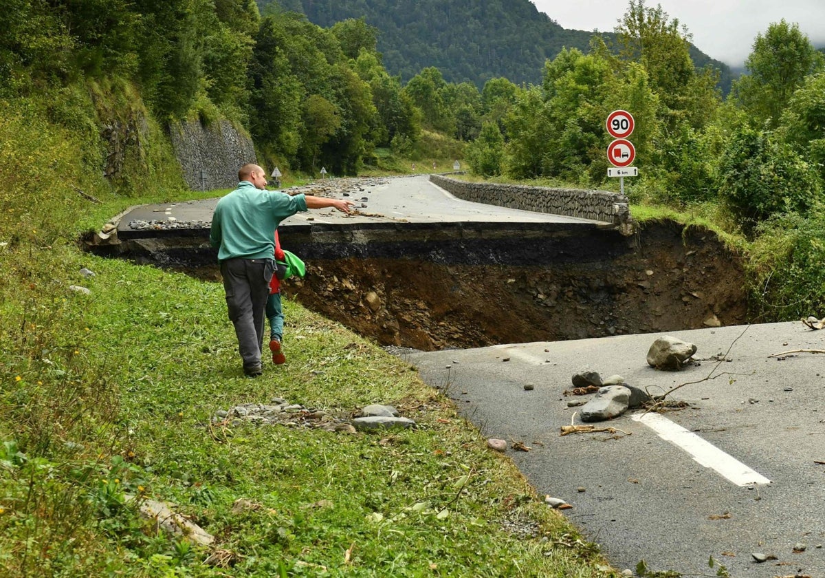 Un hombre camina con su hijo después de que un corrimiento de tierras dañara la carretera nacional Col du Somport 134 en dirección a España tras las fuertes lluvias cerca de la ciudad de Urdos, suroeste de Francia