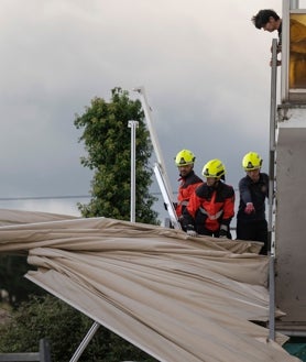 Imagen secundaria 2 - Arriba, un árbol caído sobre un banco a causa del viento provocado por la borrasca Kirk en Baracaldo (Vizcaya). Abajo, izquierda, la abundante lluvia registrada en Santiago y a la derecha, los bomberos de Santander retiran un toldo derribado por el viento en la capital cántabra