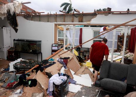 Imagen secundaria 1 - Residentes de Orlando (Florida) hacen acopio de sacos terreros (arriba). En Fort Myers se dejan notar los efectos de un tornado y un hombre protege un inmueble con planchas de madera