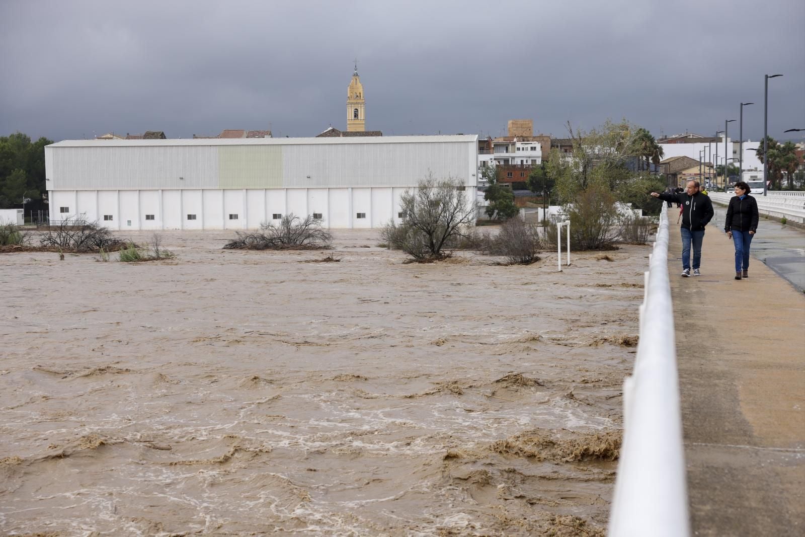 Dos personas contemplan la crecida del río Magre a su paso por Alfarp (Valencia)