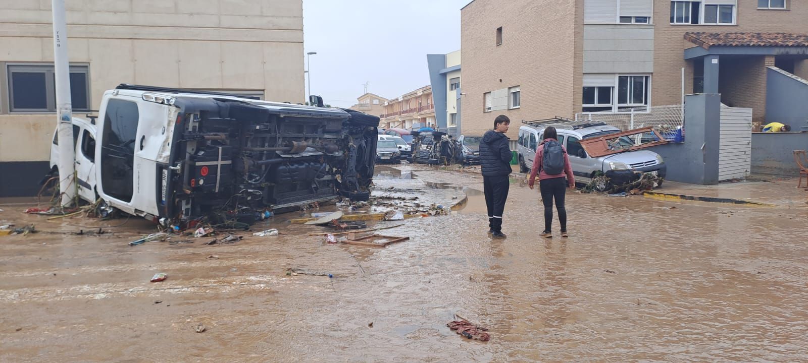 Un camión volcado en Paiporta que ha quedado volcado por la DANA con dos personas observando
