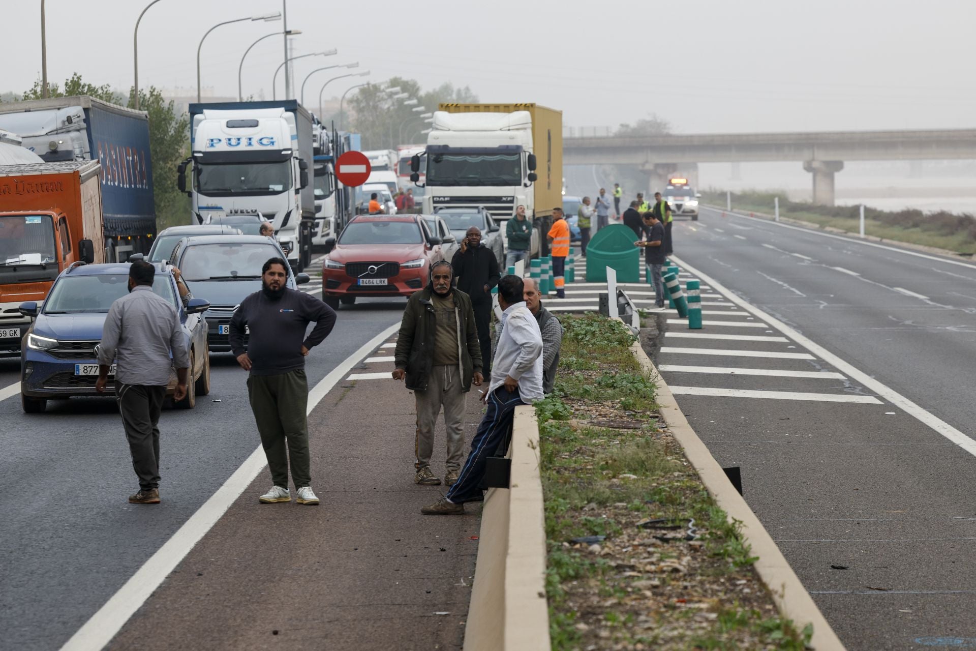Varias personas hablan en la entrada de Valencia debido a las retenciones causadas por la DANA