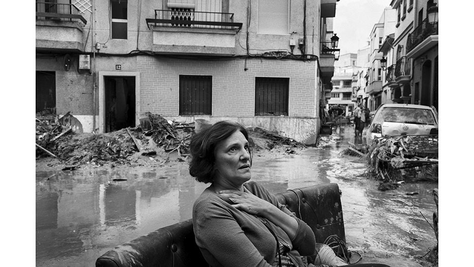 Una muler observa sentada en la calle los restos de su casa que ha sido devorada por el lodo tras el paso de la Dana en Paiporta