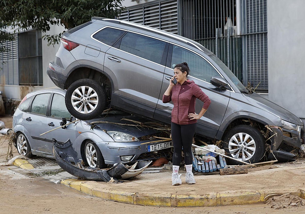 Una vecina habla por teléfono junto a dos coches destrozados