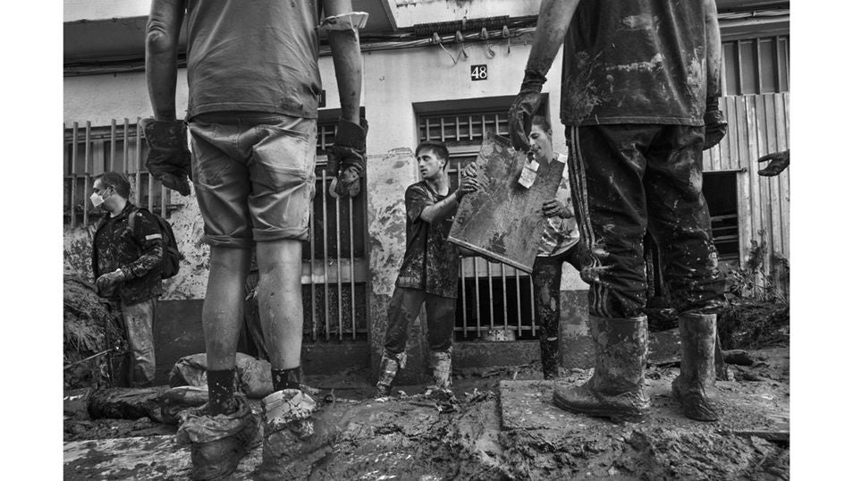 Varios voluntarios, durante las labores de desescombro y limpieza del barro en la localidad de Paiporta, destrozada por la riada