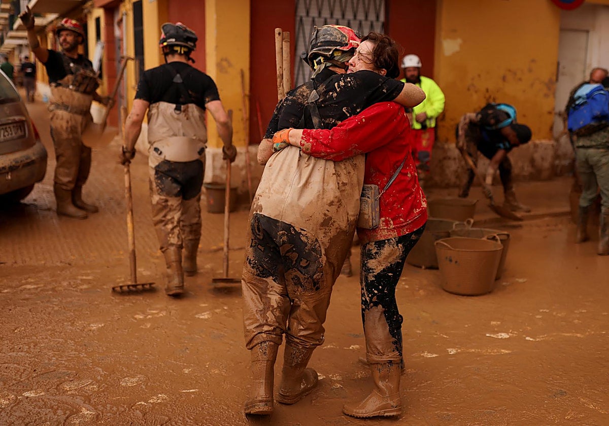 Una vecina de Sedaví se abraza a un efectivo de la Unidad Militar de Emergencias que participa en tareas de limpieza en la zona, golpeada por la DANA