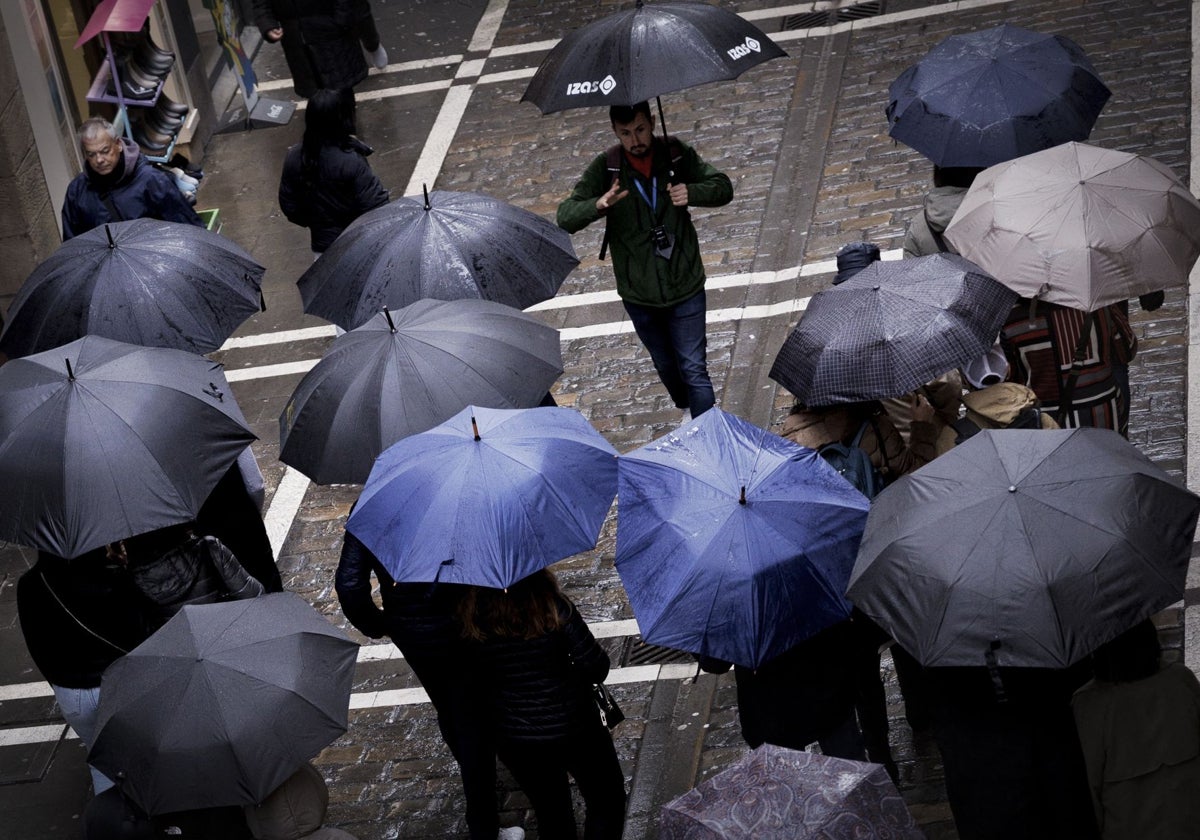 Un grupo de turistas se protege de la lluvia con sus paraguas en Pamplona