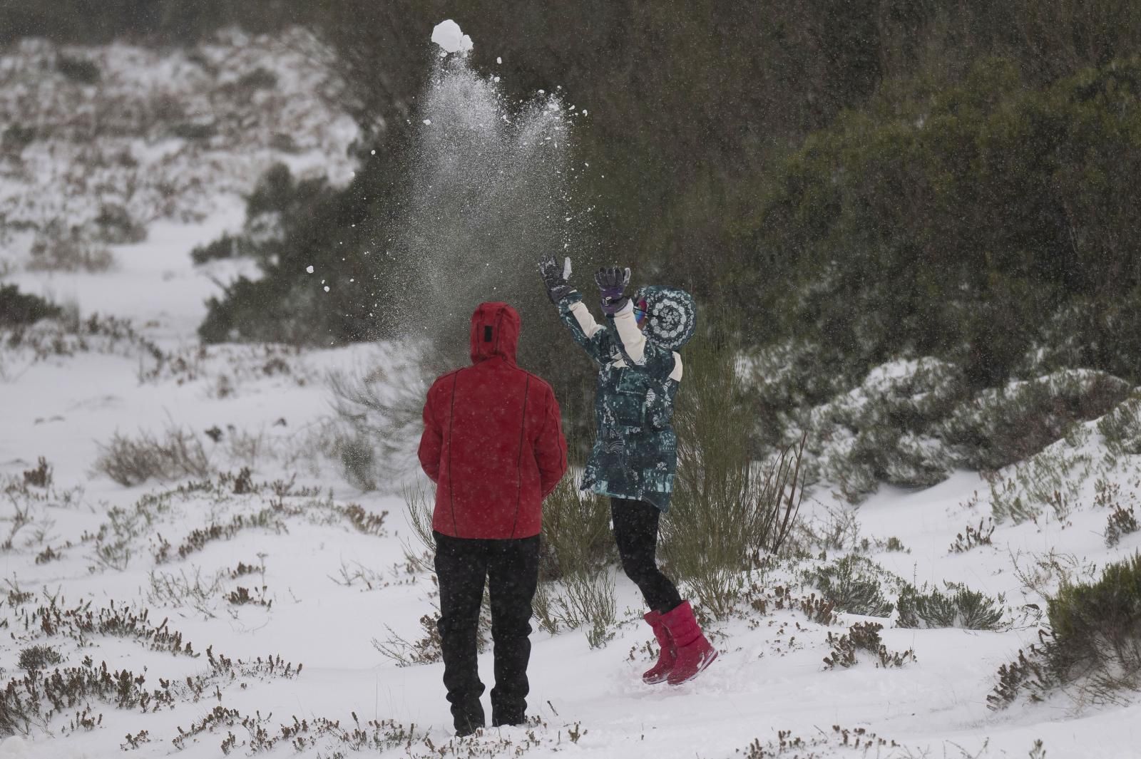 Varias personas juegan con la nieve caída en la localidad cántabra de la Lomba 