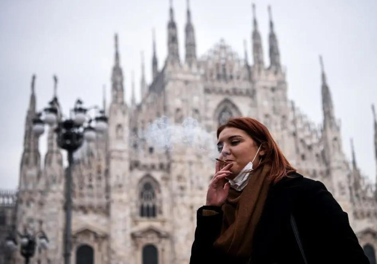 Una mujer fuma un cigarrillo en la Piazza del Duomo de Milán