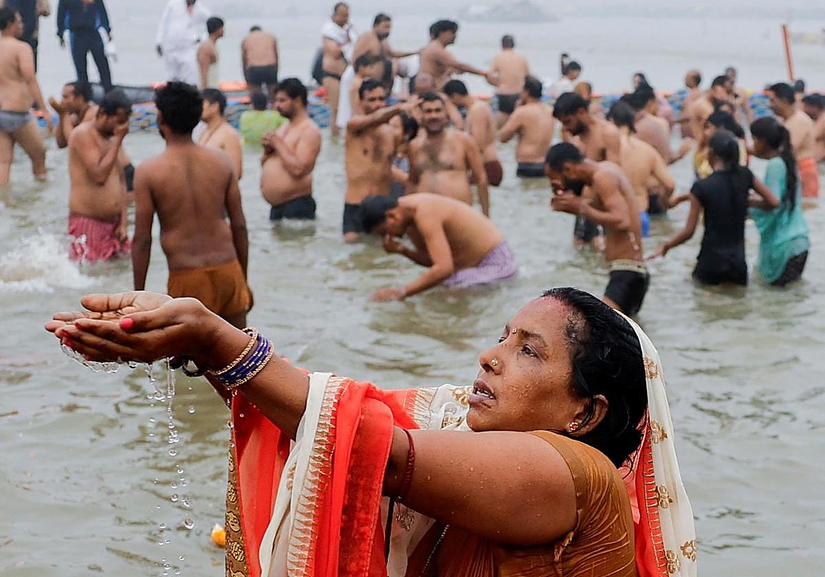 Una devota reza mientras se da un baño sagrado en Sangam, la confluencia de los ríos Ganges y Yamuna