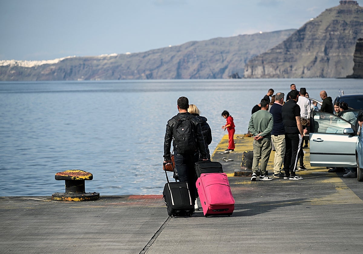 Varios habitantes y turistas salen de la isla griega