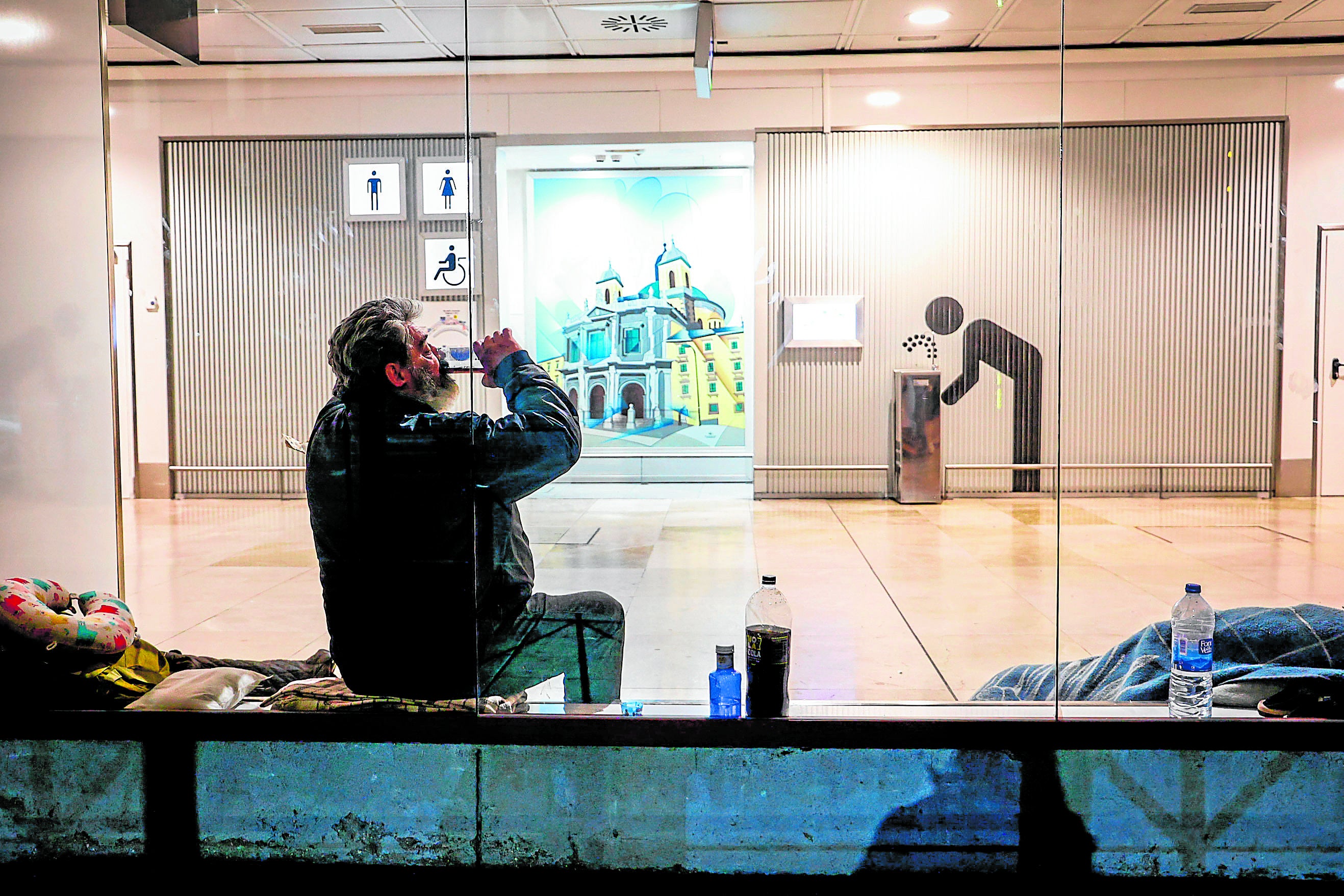 Imagen principal - Paz no quiere revelar su nombre porque nadie sabe dónde está. Unas 300 personas sin un hogar, como el rumano Florie, de 56 años, viven bajo este techo de la capital