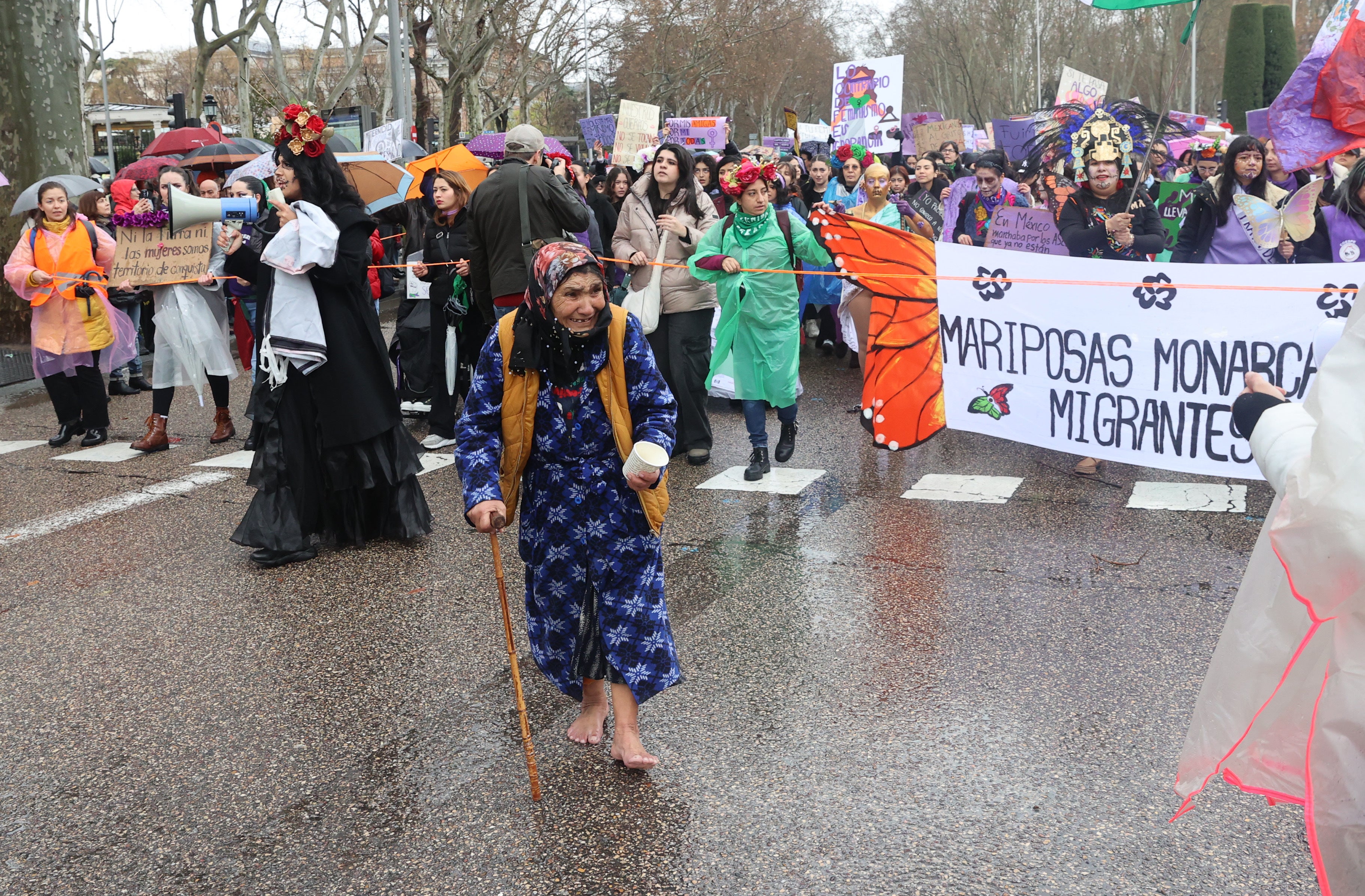 Una mujer pide limosna en plena manifestación del 8M en Madrid