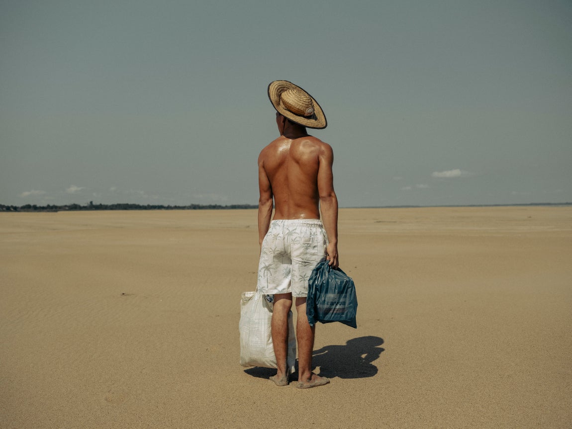 Un joven le lleva comida a su madre, que vive en la aldea de Manacapuru (Brasil). Antes se podía acceder a la aldea en barco, pero debido a la sequía, debe caminar dos kilómetros por el lecho seco del río Solimões para llegar hasta ella