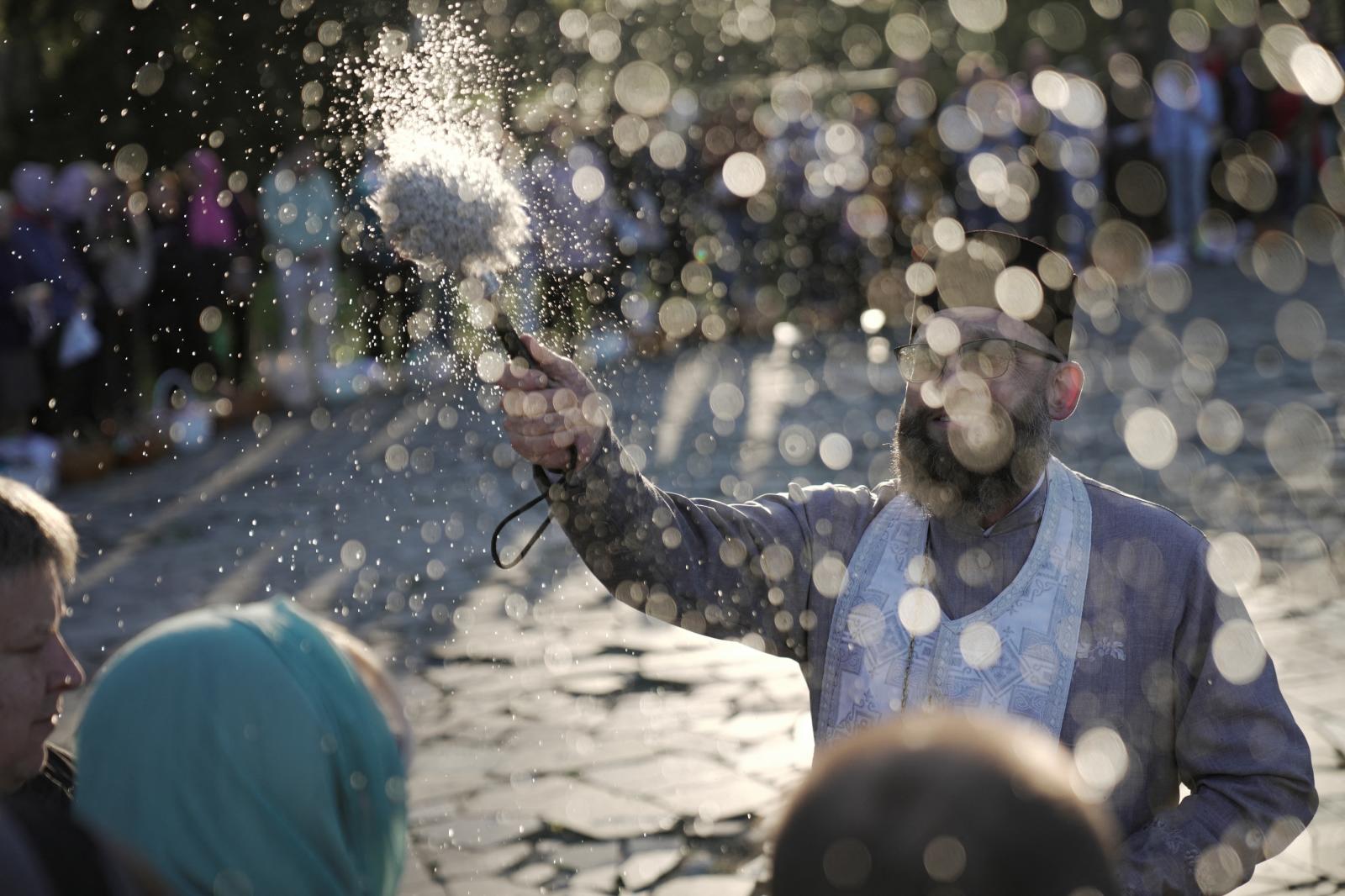 Ofrece la bendición con el agua a los asistentes a la ceremonia frente a la iglesia de San Andrés en la ciudad de Bucha, en la región de Kiev.