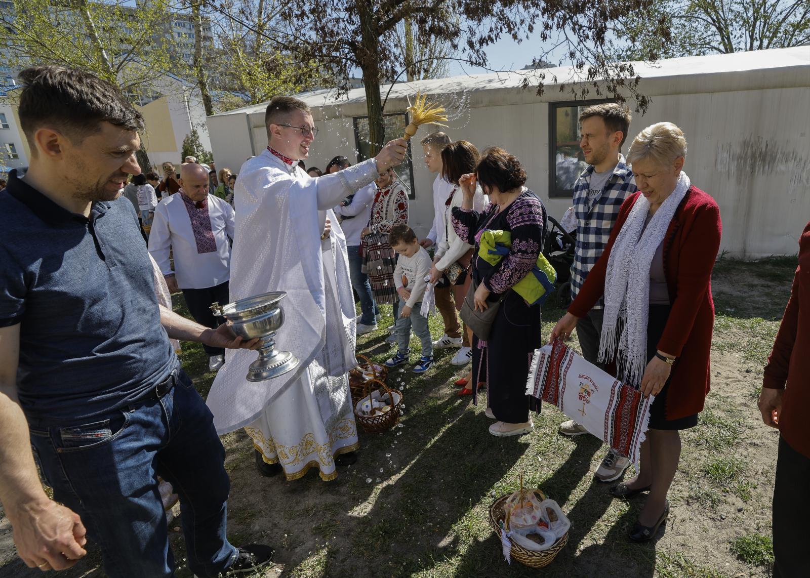 Un sacerdote ucraniano bendice a los creyentes y sus cestas que contienen huevos pintados y kulichi, un pastel tradicional de Pascua, durante la misa de Pascua en la iglesia greco-católica temporal de los Santos Boris y Glib, en Kiev.