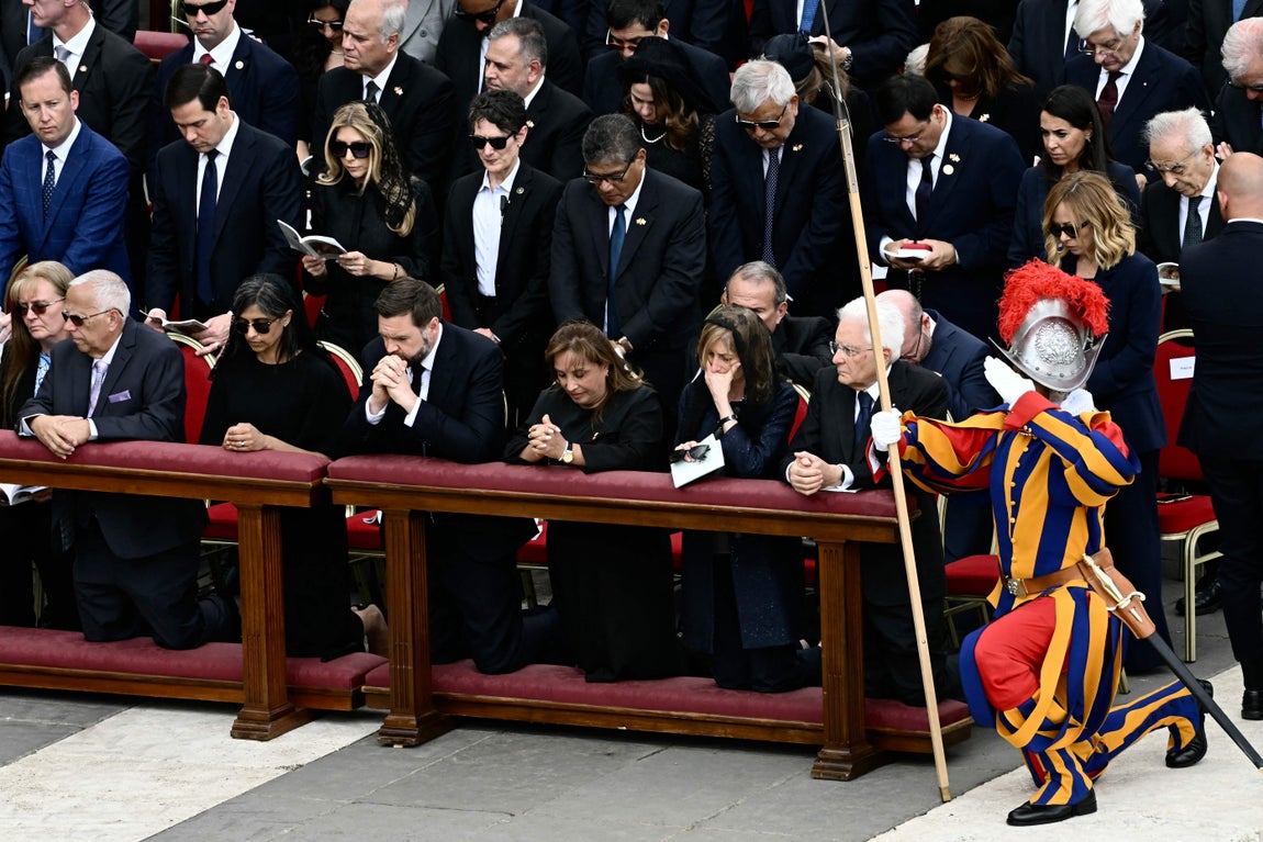 Un miembro de la Guardia Suiza se arrodilla en la oración. En el banco, el vicepresidente de Estados Unidos, JD Vance, junto a su esposa
