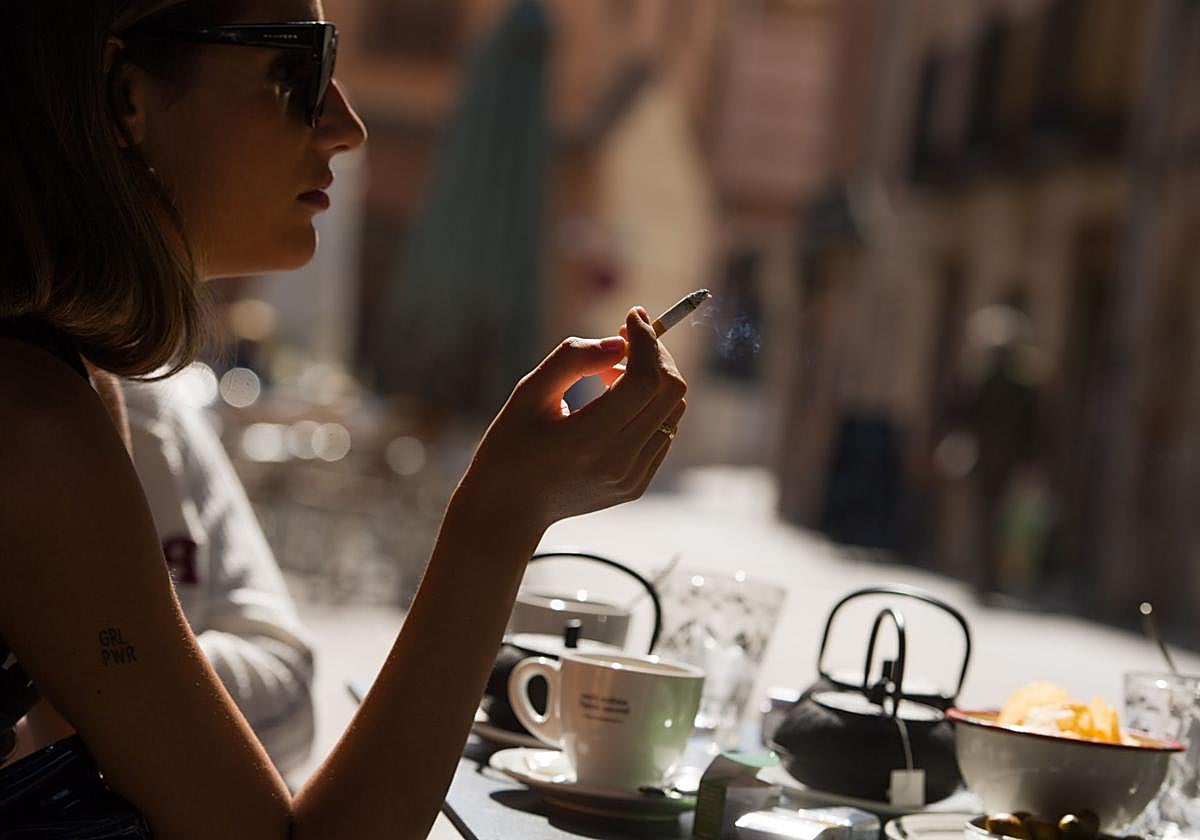 Una mujer fumando en una terraza en una imagen de archivo.