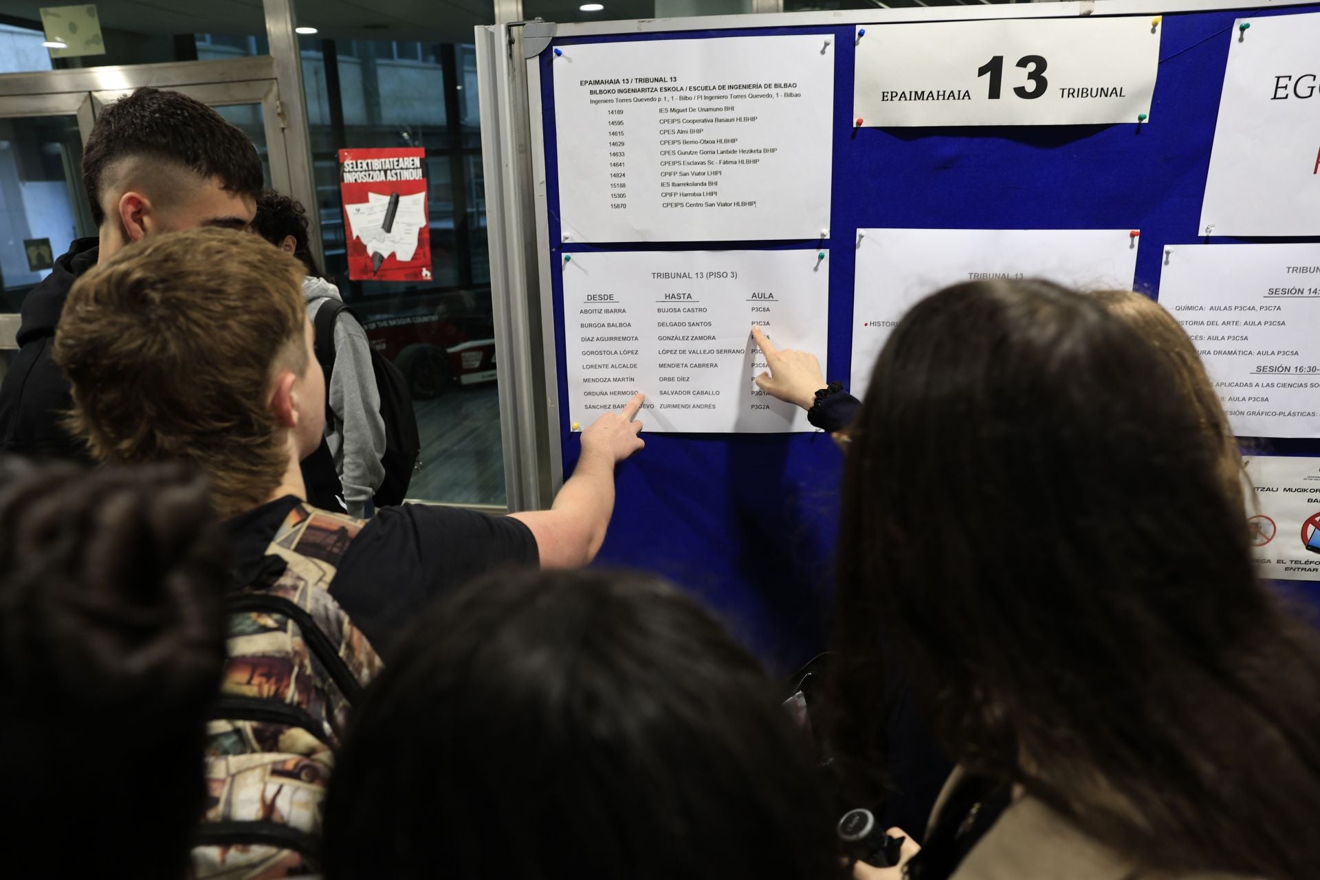 Grupos de alumnos consultan el aula que les corresponde para examinarse en la primera jornada de la PAU en Bilbao.