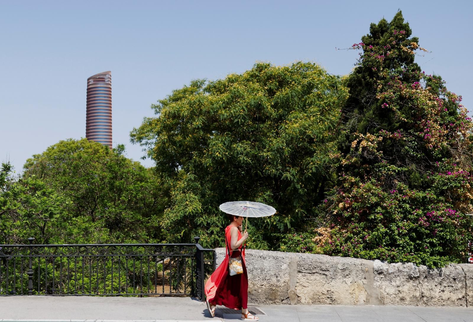 Una mujer se protege del calor del sol con una sombrilla en Sevilla.