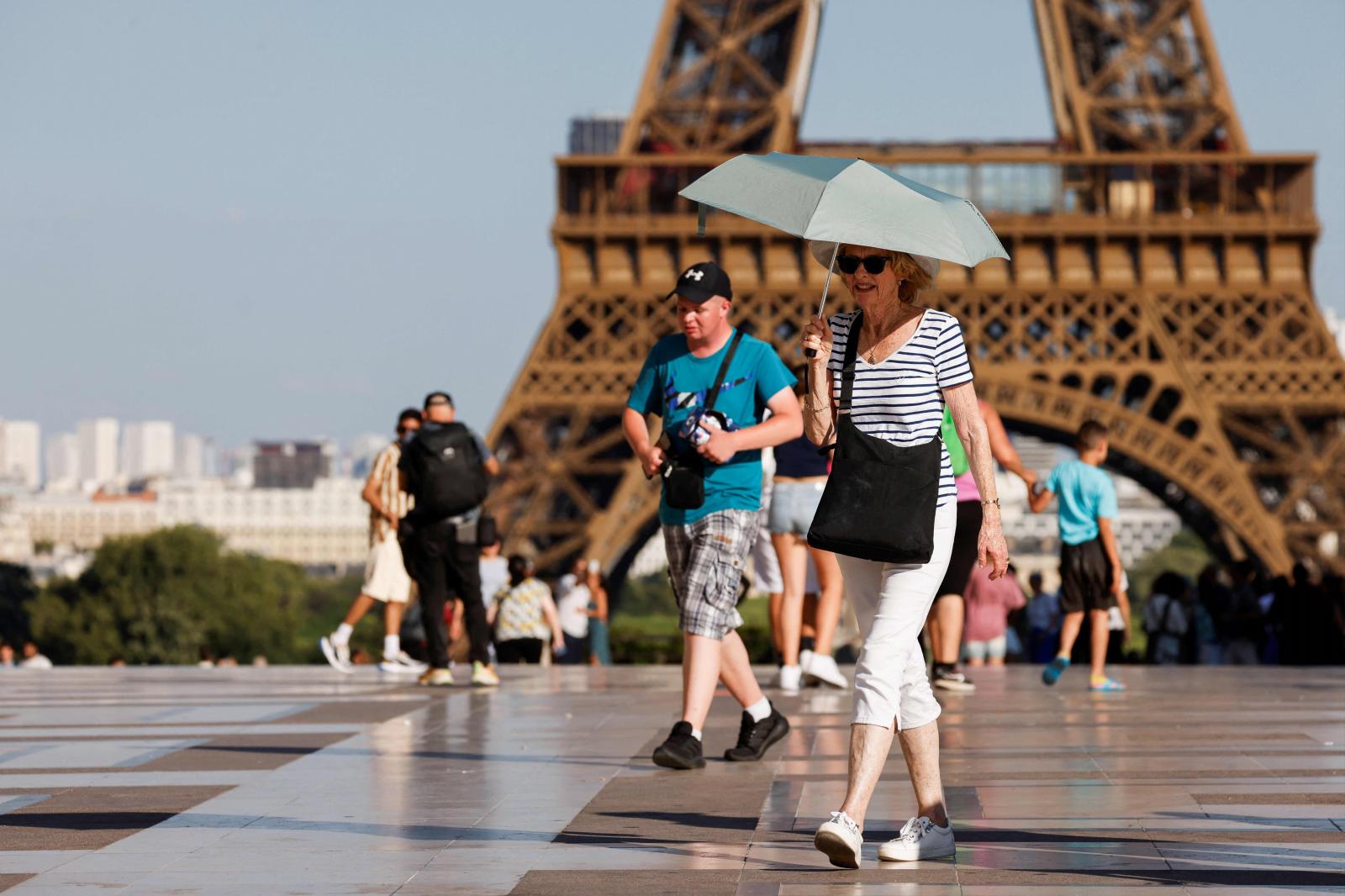 Una turista se protege del sol con un paraguas durante una ola de calor cerca de la Torre Eiffel, en la plaza Trocadero, en París