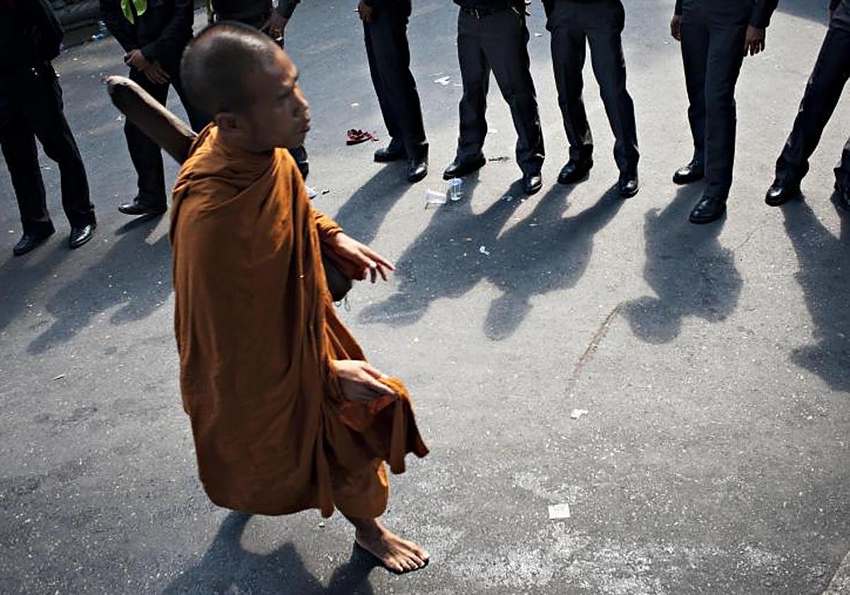 Un monje budista pasa frente a soldados y policías en Bangkok
