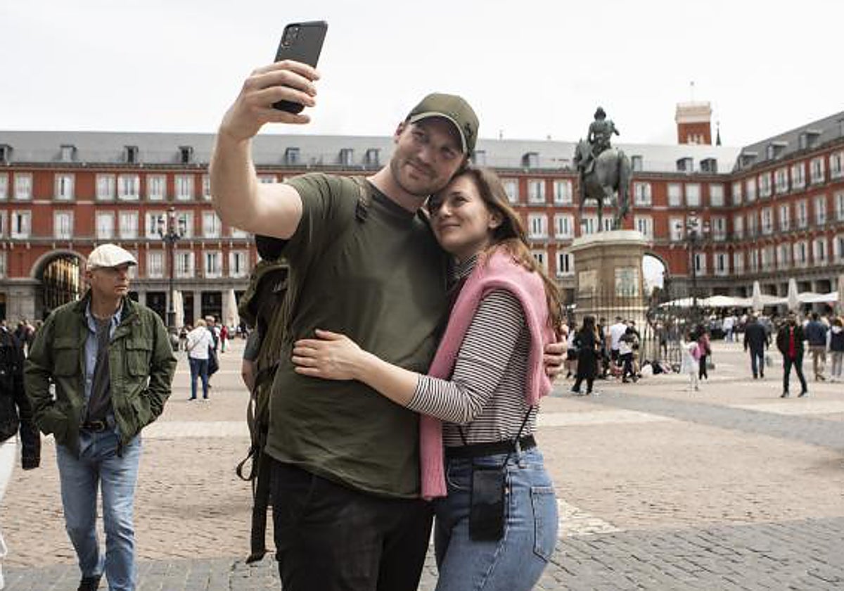 Una pareja de jóvenes se hace una fotografía en la Plaza Mayor de Madrid, en el centro