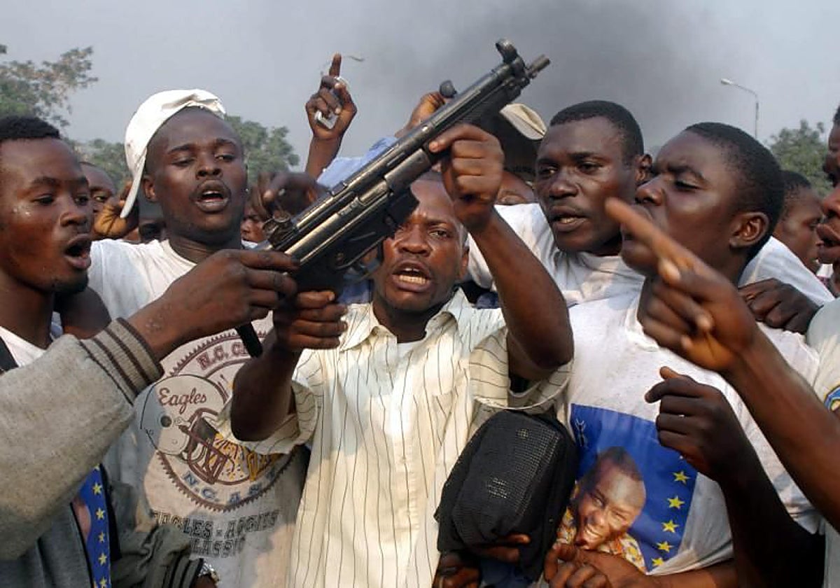 Saqueadores levantan un arma de una iglesia incendiada en Kinshasa (República Democrática del Congo)