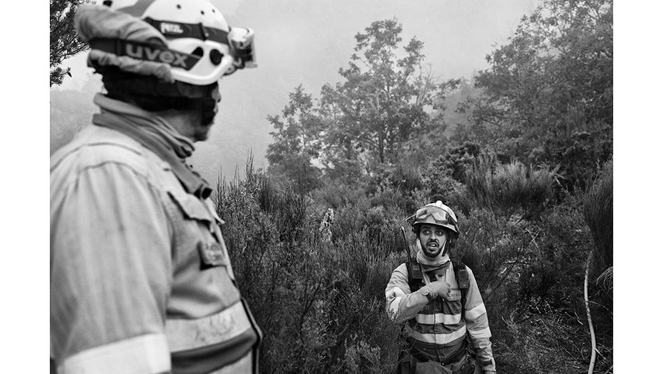Un bombero da instrucciones a su compañero en medio de la ladera. En Fornela, la comunicación en el terreno resulta esencial. Con el viento cambiando de dirección y los focos reavivándose a cada momento, la rapidez con la que se transmiten órdenes marca la diferencia entre contener el fuego o perder la línea.