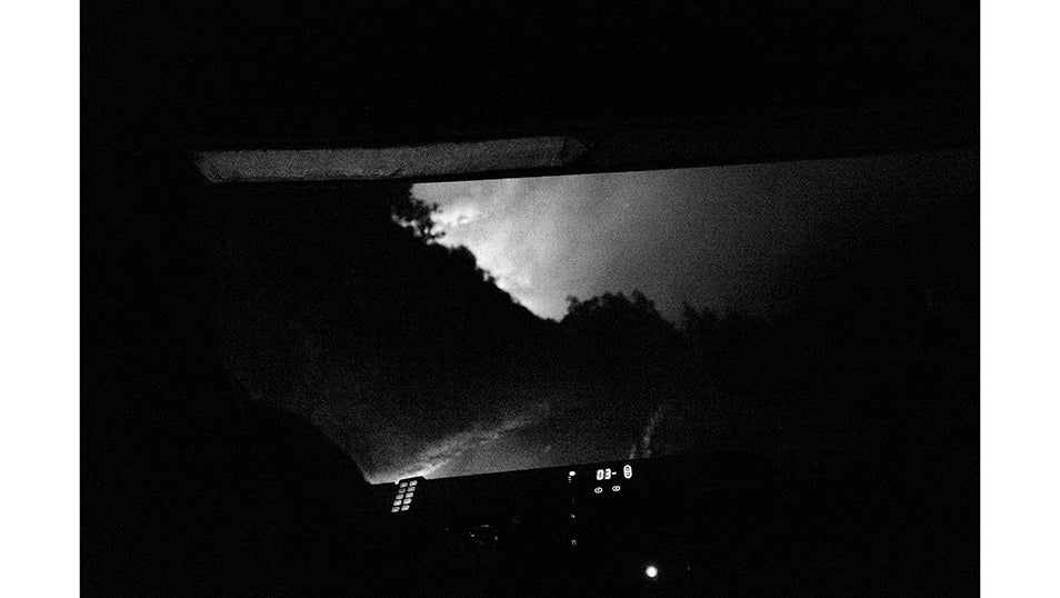 La silueta del fuego aparece al fondo de la carretera vista desde la cabina de un camión de bomberos que se aproxima al frente. En Fornela, los equipos se han visto obligados a trabajar de día y de noche para contener un incendio que no da tregua. Cada relevo nocturno significa volver a enfrentarse a un terreno escarpado, con poca visibilidad y bajo la presión constante del viento cambiante.